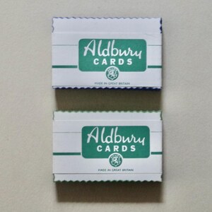 Peut inclure: Deux boîtes de cartes blanches avec le texte vert "Aldbury CARDS". Les boîtes ont un bord festonné et sont étiquetées "Made in Great Britain". Les boîtes sont empilées l'une sur l'autre.