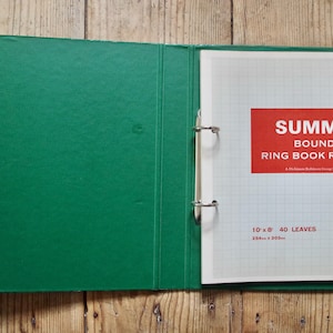 May include: Open green binder with a white grid paper refill. The refill has a red label that reads "SUMMIT BOUND RING BOOK REFILL". The refill is 254mm x 203mm and contains 40 leaves.