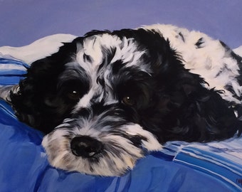 May include: A black and white dog with fluffy fur is lying on a blue and white striped blanket. The dog's head is resting on the blanket, and its eyes are closed.