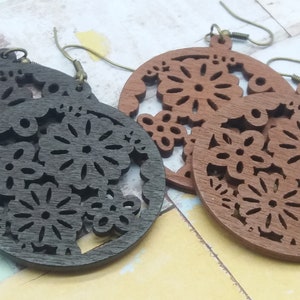 Pode incluir: Dois pares de brincos de madeira com um design floral. Um par &eacute; castanho escuro, o outro &eacute; castanho claro. Os brincos s&atilde;o circulares com intrincados padr&otilde;es recortados de flores e folhas e t&ecirc;m ganchos de orelha cor de bronze.