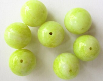May include: Seven round, light green glass beads with a white marbled pattern. The beads have a small hole in the center.