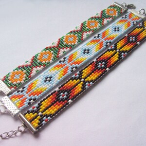 May include: Three beaded bracelets with colorful geometric patterns. The bracelets are made with small, colorful beads and have silver clasps.