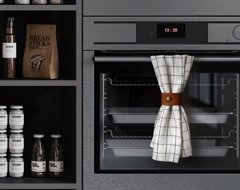 May include: A modern kitchen interior with dark gray cabinetry and built-in appliances. Shelves display jars, bottles, and paper bags labeled "BREAD STICKS." A checkered towel hangs in the oven. The time 13:25 is displayed on the oven and coffee maker.