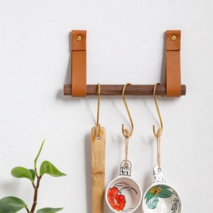 A Hanging Dowel Kit installed on the wall with kitchen accessories hanging.