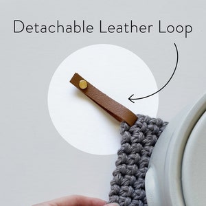 May include: Gray crocheted pot holder with a brown leather loop. The loop is detachable and has a gold metal button.