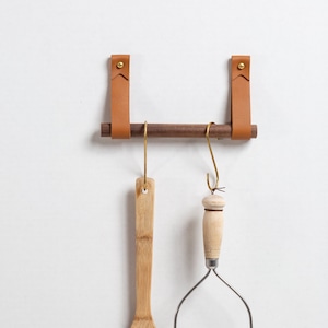 A Hanging Dowel Kit installed on the wall with kitchen accessories hanging.