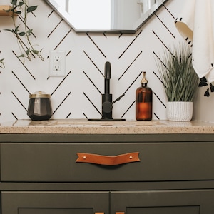 Leather Handles installed on a green vanity in a bathroom.