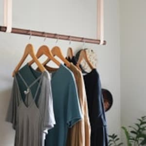 Leather Suspension Straps and a wooden dowel used for a Garment Rack in the corner of a bedroom.