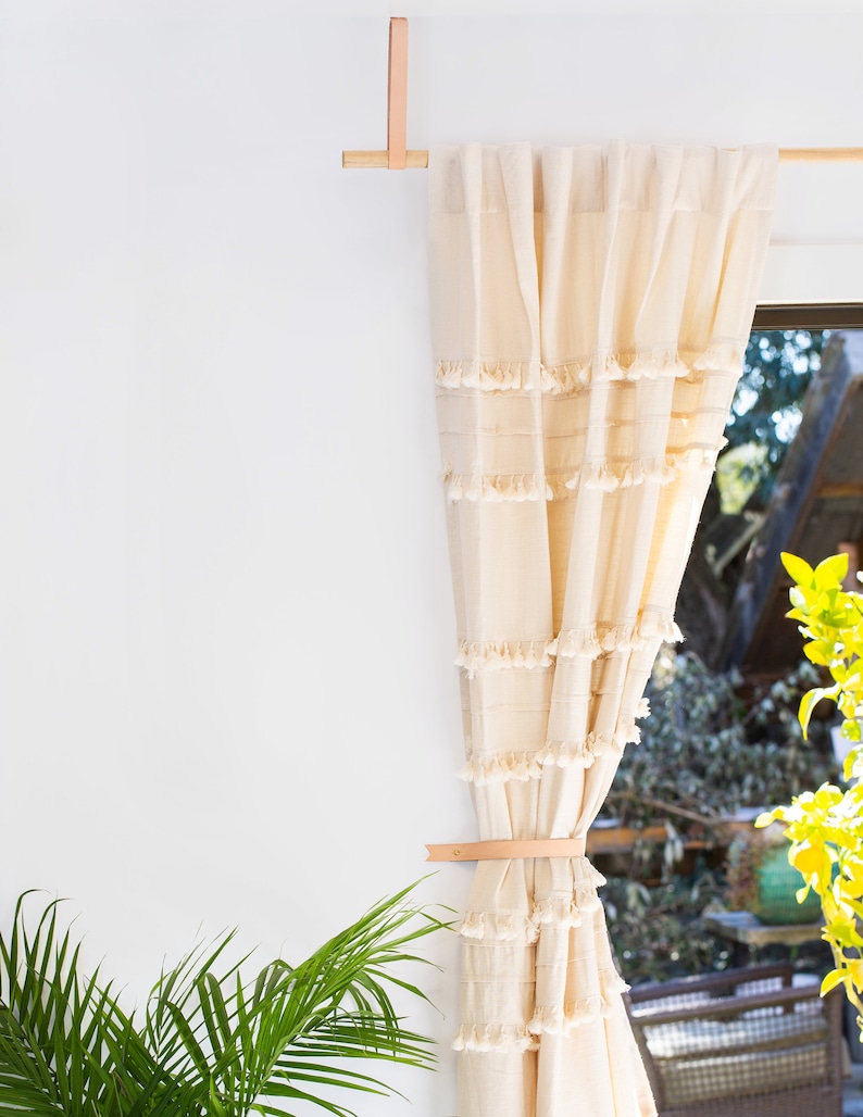 Curtains hanging from a wooden dowel and Leather Suspension Straps.