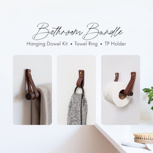 Il kit moderno per accessori da bagno include un porta rotolo di carta igienica da parete in pelle, un portasciugamani da bagno in legno e un piccolo gancio per asciugamani nero.