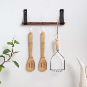 A Hanging Dowel Kit installed on the wall with kitchen accessories hanging.