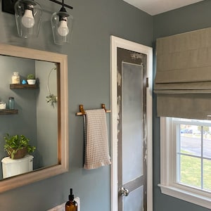 A wooden dowel used to hang a towel in a bathroom.