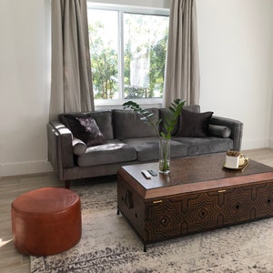 Curtains hang from Leather Suspension Straps in a living room window behind a sofa.