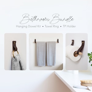 Il kit moderno per il bagno include un porta rotolo di carta igienica da parete in pelle, un portasciugamani da bagno in legno e un piccolo gancio per asciugamani in ottone dorato.