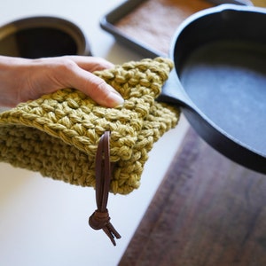 Model holding cast iron pan covering the handle with a pot holder.