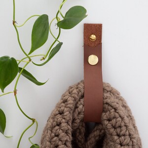 Medium Leather Snap Strap installed on the wall and with a cowel scarf looped inside the strap.