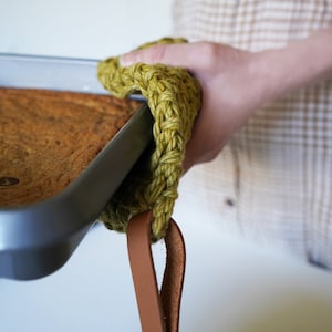Model holding a hot baking dish with a pot holder.