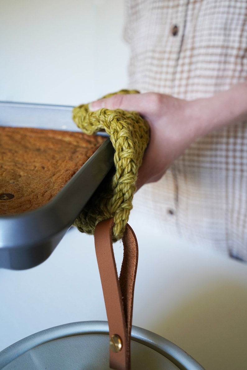 Model holding a hot baking dish with a pot holder.