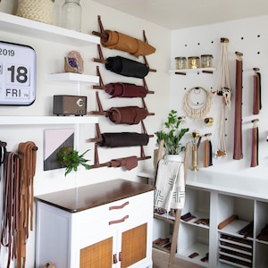 A craft studio using dowels to hang leather hides.