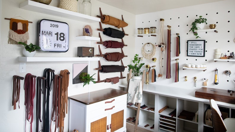 A craft studio using dowels to hang leather hides.