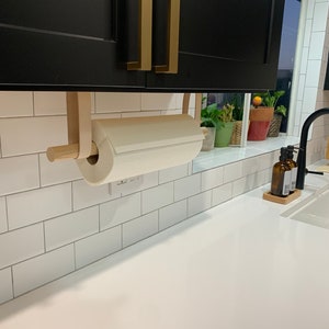 A Paper Towel Holder hangs under the counter cabinets. Two Suspension Straps and a wooden dowel hold the paper towel.