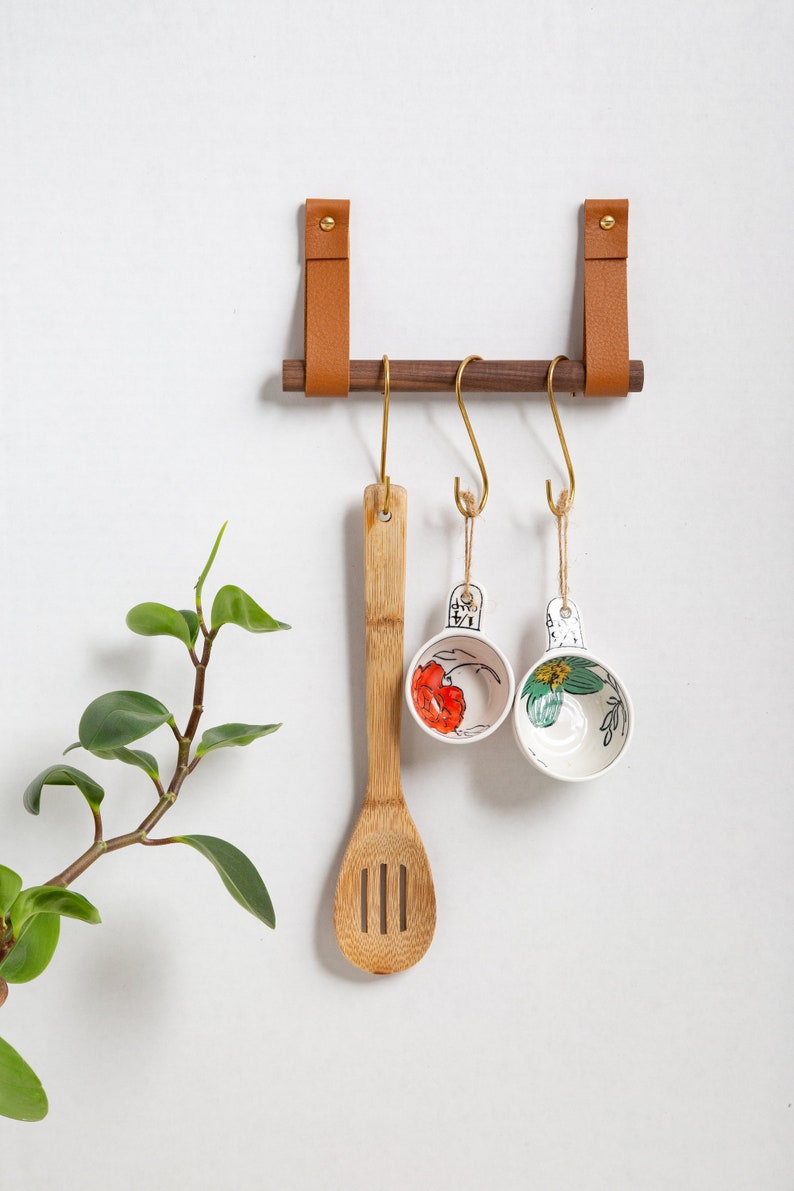 A Hanging Dowel Kit installed on the wall with kitchen accessories hanging.