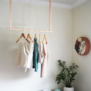 Leather Suspension Straps and a wooden dowel used for a Garment Rack in the corner of a bedroom.