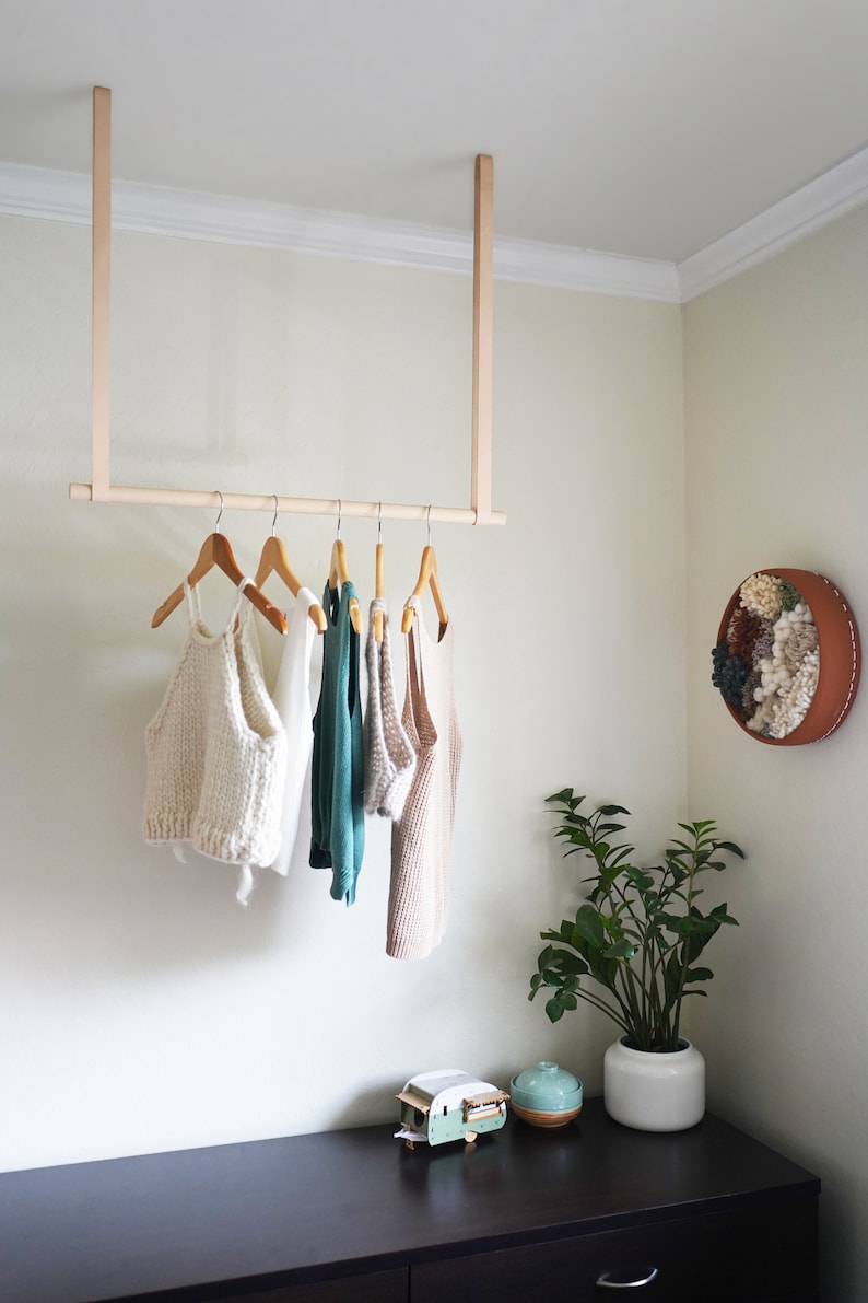 Leather Suspension Straps and a wooden dowel used for a Garment Rack in the corner of a bedroom.