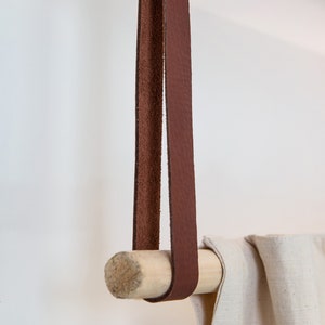 A closeup of a Leather Suspension Strap hanging a curtain with a wooden dowel.