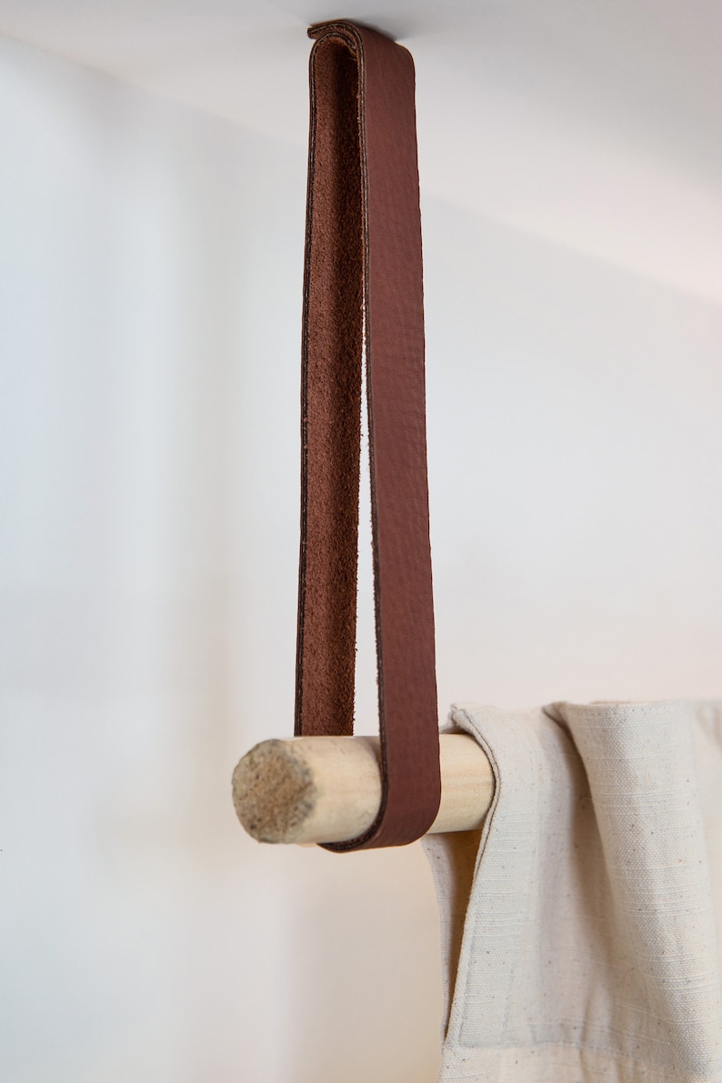 A closeup of a Leather Suspension Strap hanging a curtain with a wooden dowel.