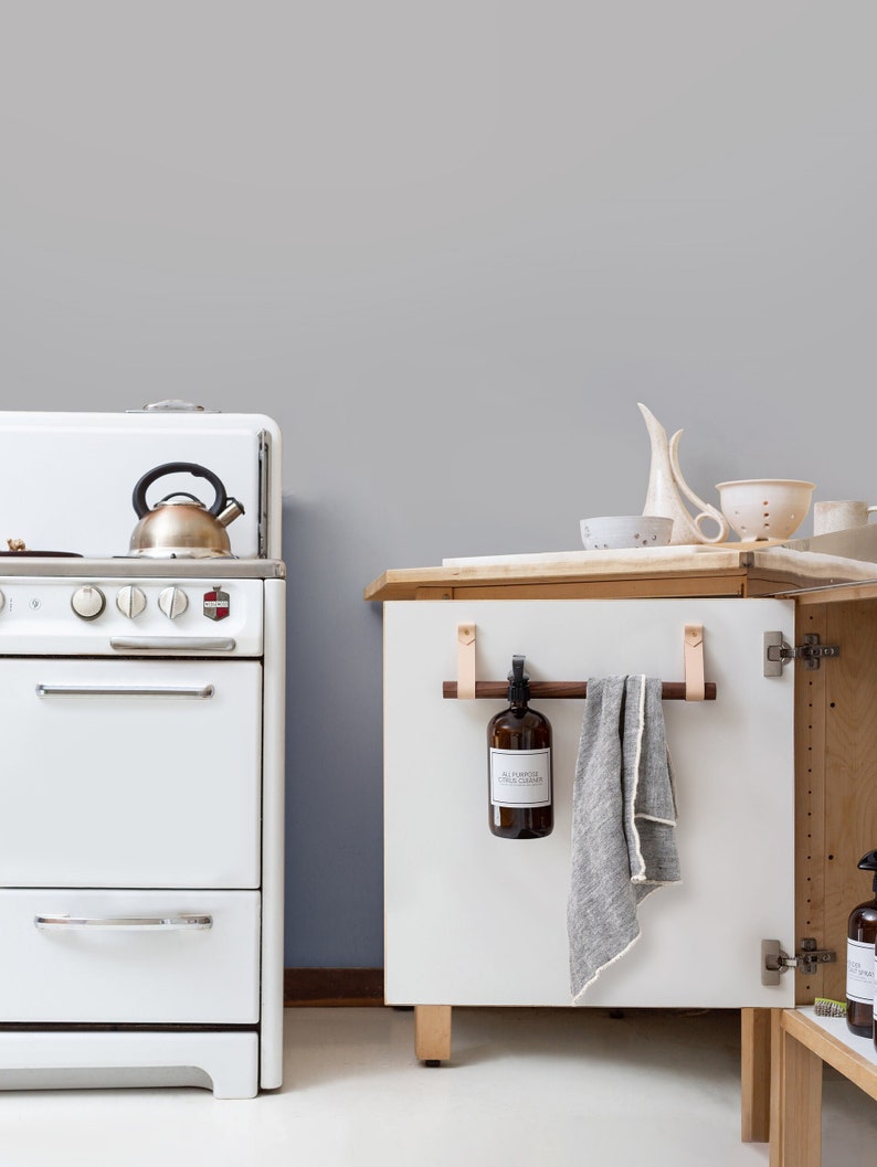 A kitchen scene of a Cabinet Rail Kit installed under the sink on a cabinet door.