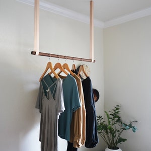 Leather Suspension Straps and a wooden dowel used for a Garment Rack in the corner of a bedroom.