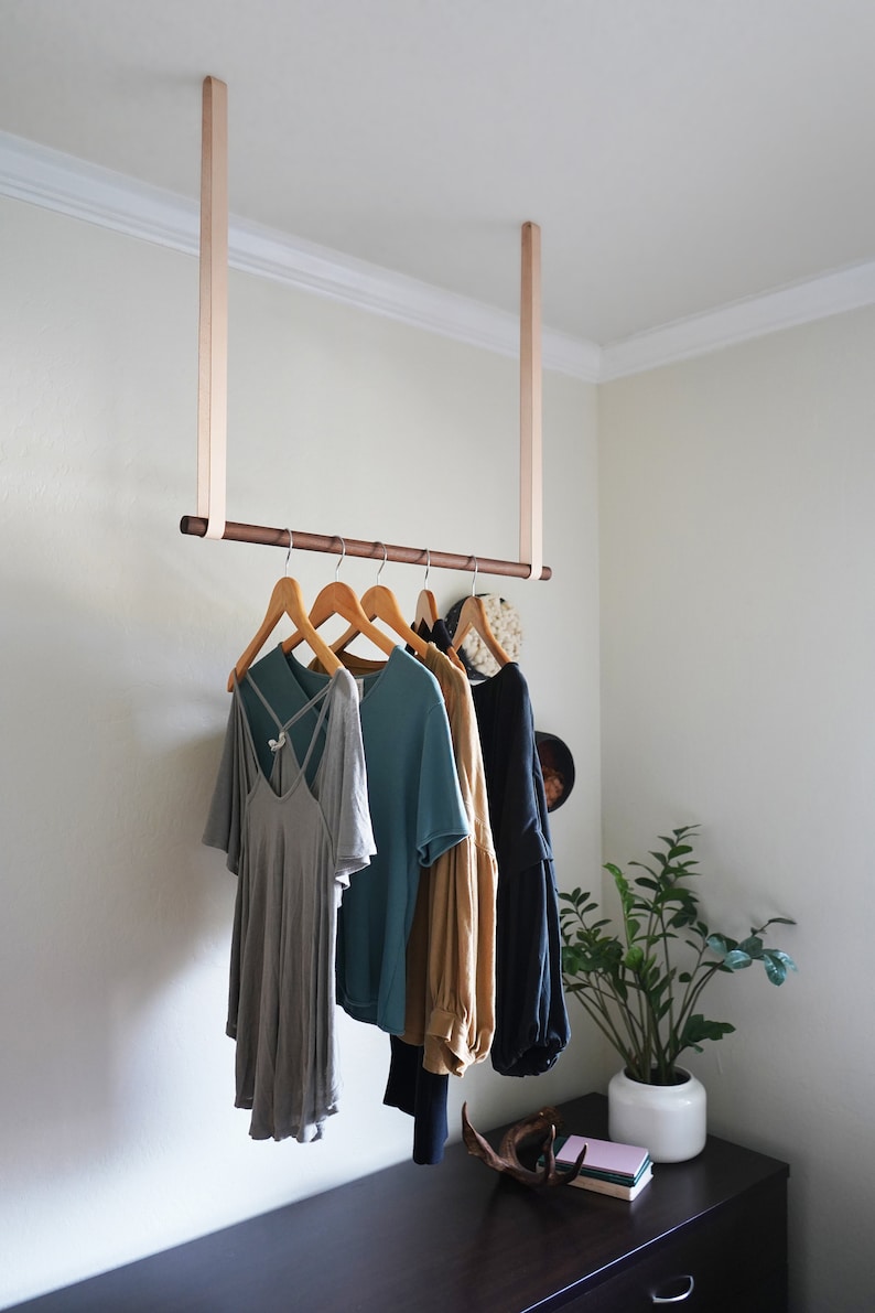 Leather Suspension Straps and a wooden dowel used for a Garment Rack in the corner of a bedroom.