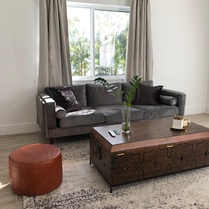 A living room scene of curtains hanging from a rod which are suspended from Leather Suspension Straps.