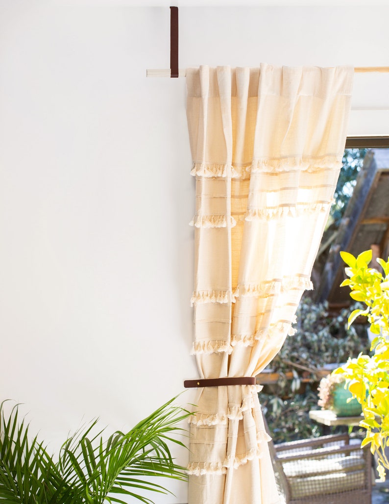 Curtains hanging from a wooden dowel and Leather Suspension Straps.