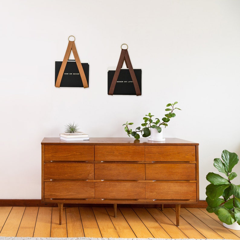 Two File Holders holding black folders on the wall above a dresser.