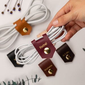 Leather Cable Holder shown wrapping a cable, with other leather cord holder surrounding it.