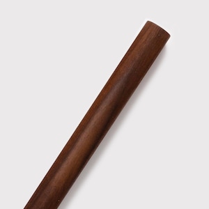 May include: A close-up shot of a dark brown, cylindrical wooden object. The wood grain is visible, and the object has a smooth, polished appearance. The object is set against a plain white background.