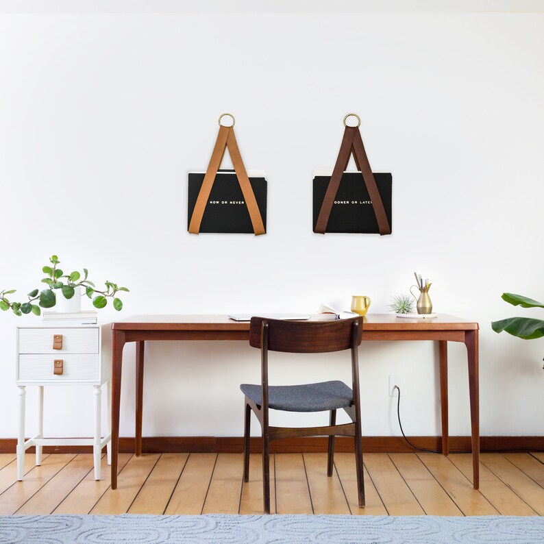 Two File Holders holding black folders on the wall above a desk.