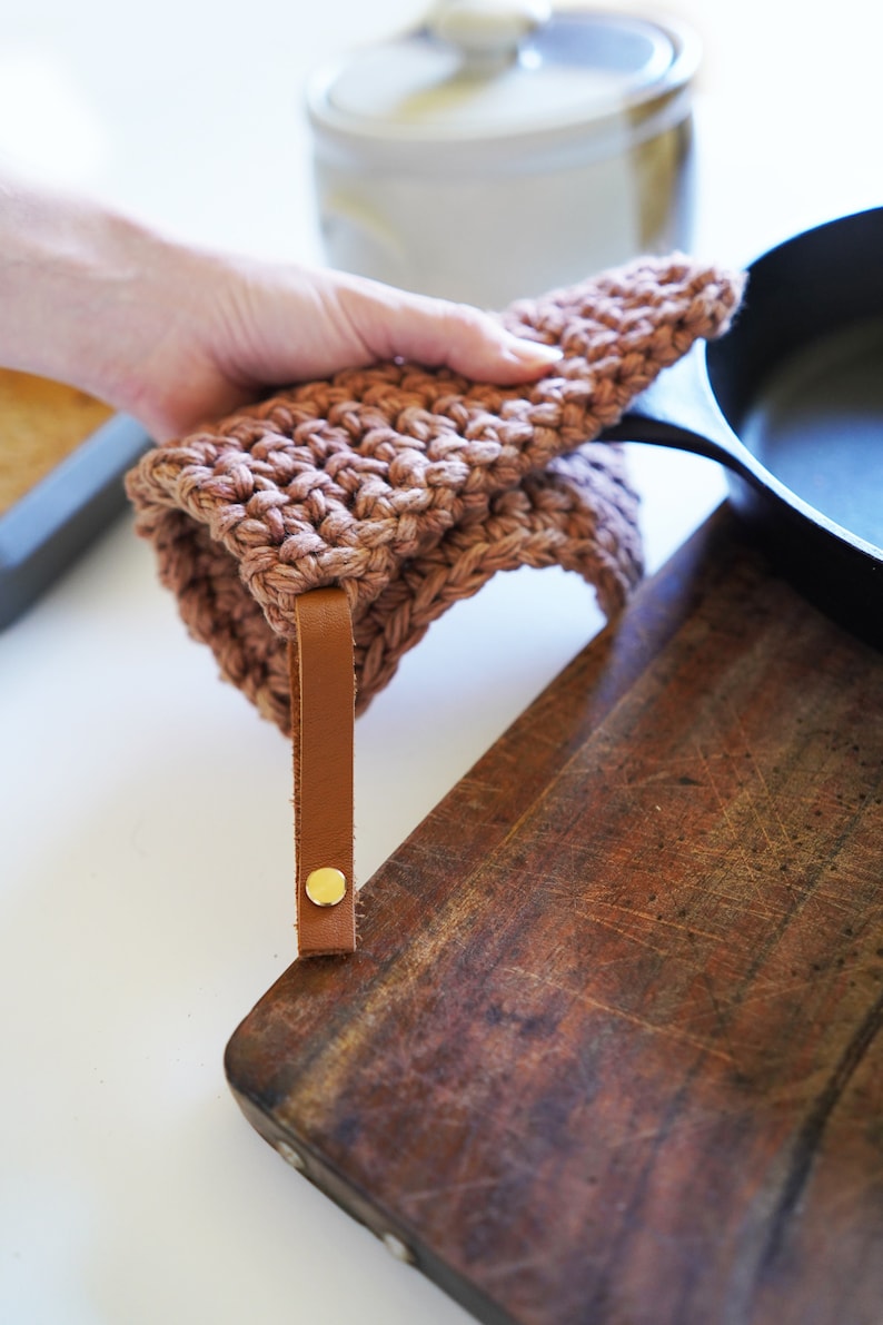 Model holding cast iron pan covering the handle with a pot holder.