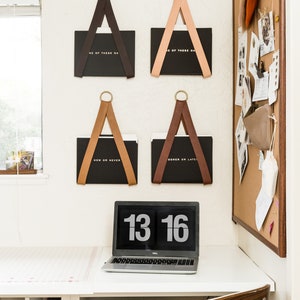 Four File Holders holding black folders on the wall with a cork message board on the right.