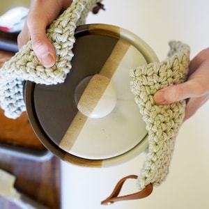 Two hands holding a hot casserole dish with pot holders.