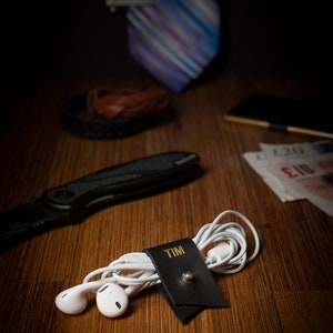 Small Leather Cord Holder displayed on an office desk wrapped around a cord.