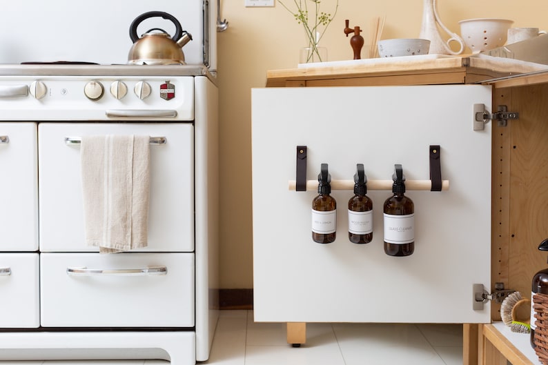 A kitchen scene of a Cabinet Rail Kit installed under the sink on a cabinet door.