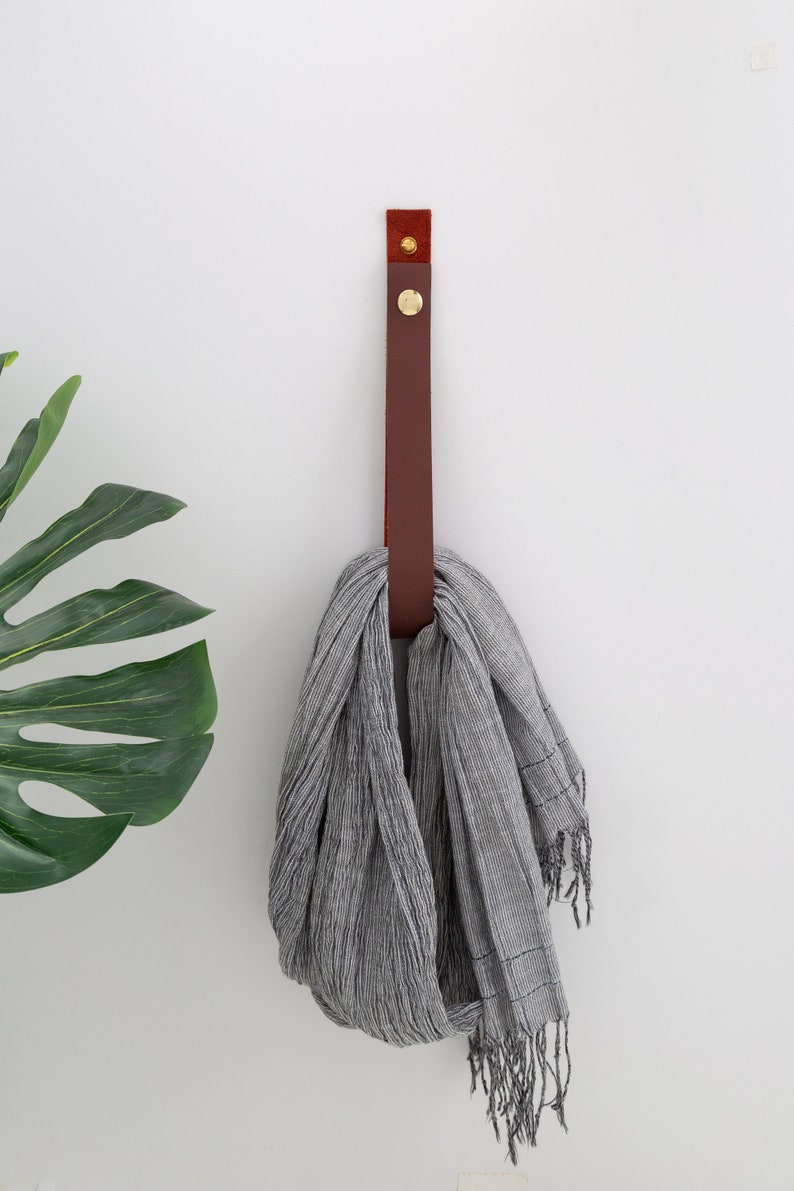 Large Leather Snap Strap installed on the wall and with a kitchen scarf looped inside the strap.