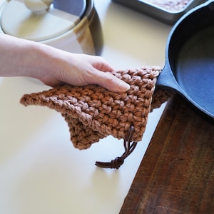 Model holding cast iron pan covering the handle with a pot holder.