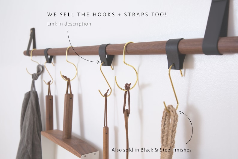 May include: A wooden wall mounted rod with black leather straps and gold metal hooks. The hooks are hanging from the rod and have brown leather straps attached to them. The text on the image reads: 'WE SELL THE HOOKS + STRAPS TOO! Link in description Also sold in Black & Steel finishes'.
