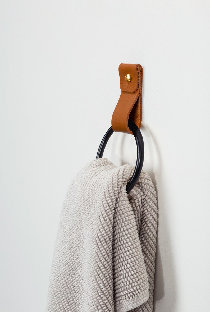 Leather Wall Strap installed on the wall and styled with a fluffy bathroom towel looped inside the metal ring.