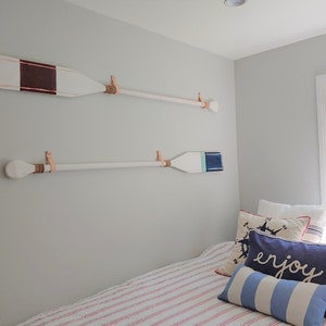 A marine themed bedroom showcases two oar paddles on the wall. 
Our Leather Wall Straps are used to hang oar paddles on the wall, the handle of the oar fits through the loop of the strap once installed.