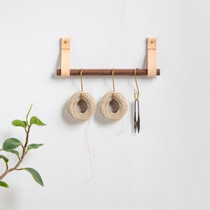 A Hanging Dowel Kit installed on the wall with kitchen accessories hanging.